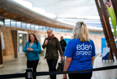 Eden Project staff member with back to the camera welcoming guests